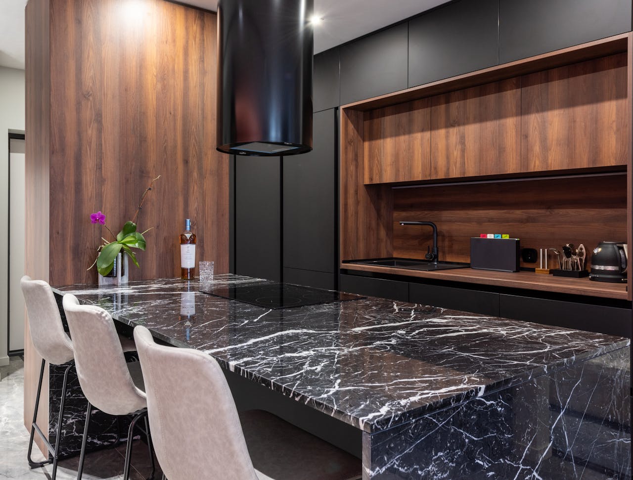 Sleek modern kitchen featuring a black marble countertop, wooden cabinets, and elegant lighting.